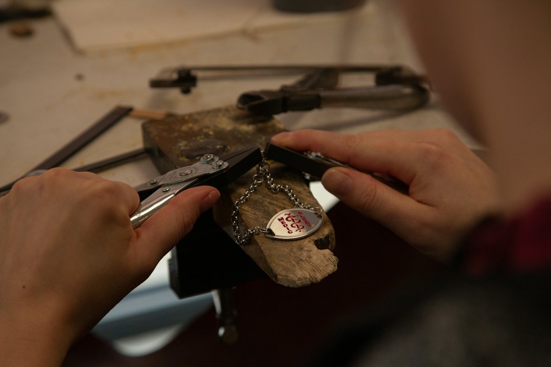Ajuste de pulseira com placa, serviço comum na pulseira grumet em Taguatinga Ourives ajustando pulseira de elos com placa na bancada, referência de pulseira grumet em Taguatinga