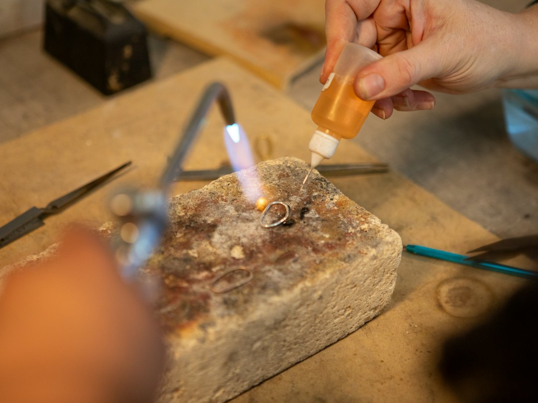 Bancada de fabricação de joias customizadas em Taguatinga Ourives soldando um anel de ouro durante a fabricação de joias customizadas em Taguatinga